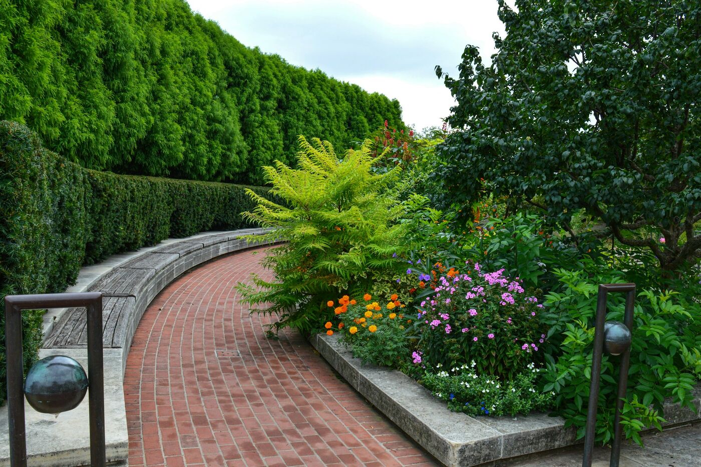 Geschwungener Klinkerweg mit farbenfroher Staudenbepflanzung in einem privaten Garten