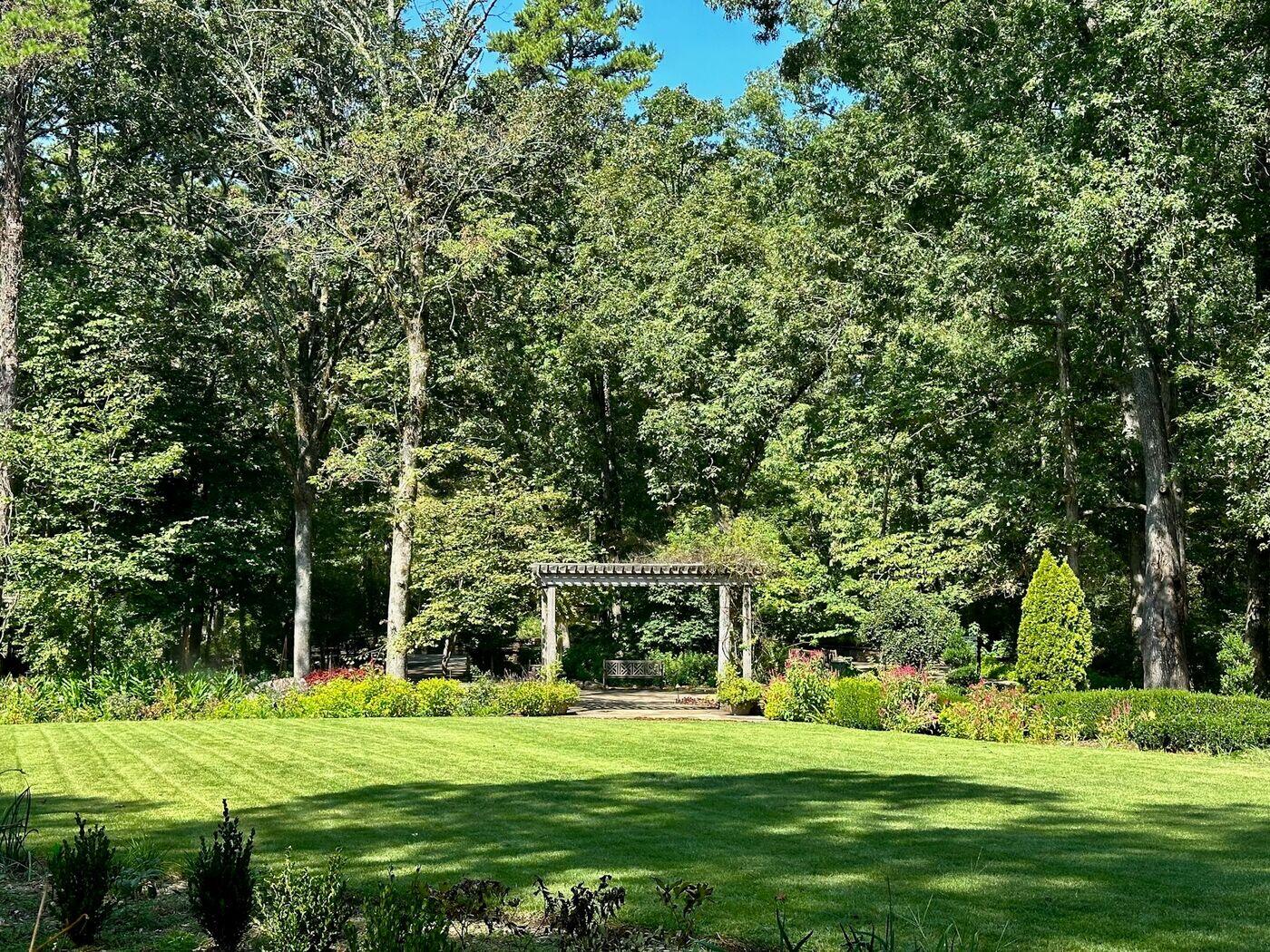 Weitläufige, frisch angelegte Rasenfläche mit Beeteinfassung und Holzpergola