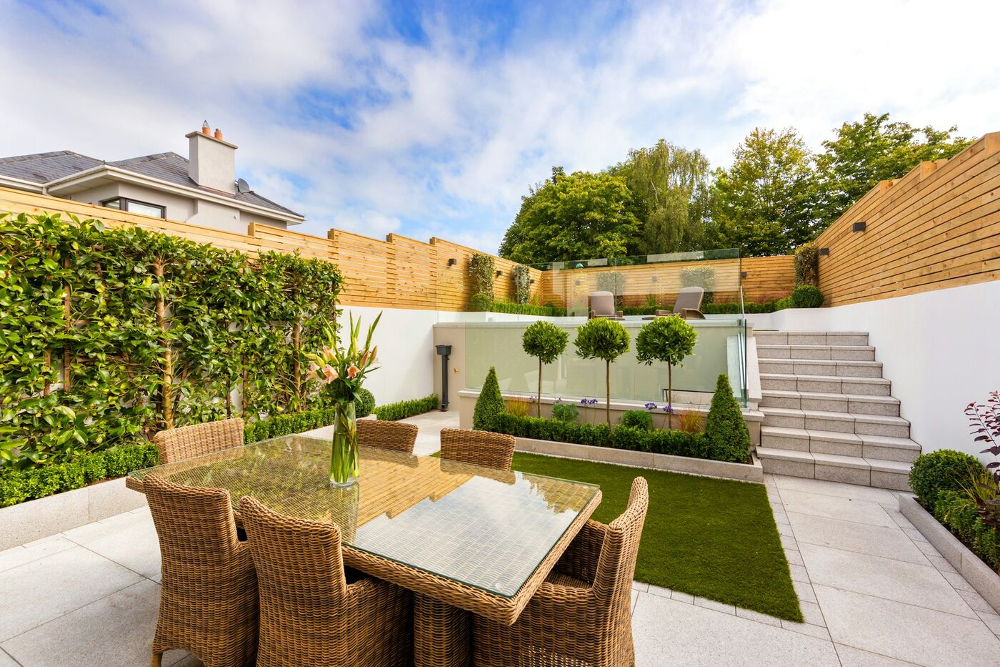 Moderne Terrasse mit großformatigen Platten, Sitzgruppe und begrüntem Sichtschutz